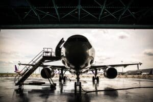 A aeroplane with stairs at the left side sits at the entrance of an aircraft hangar