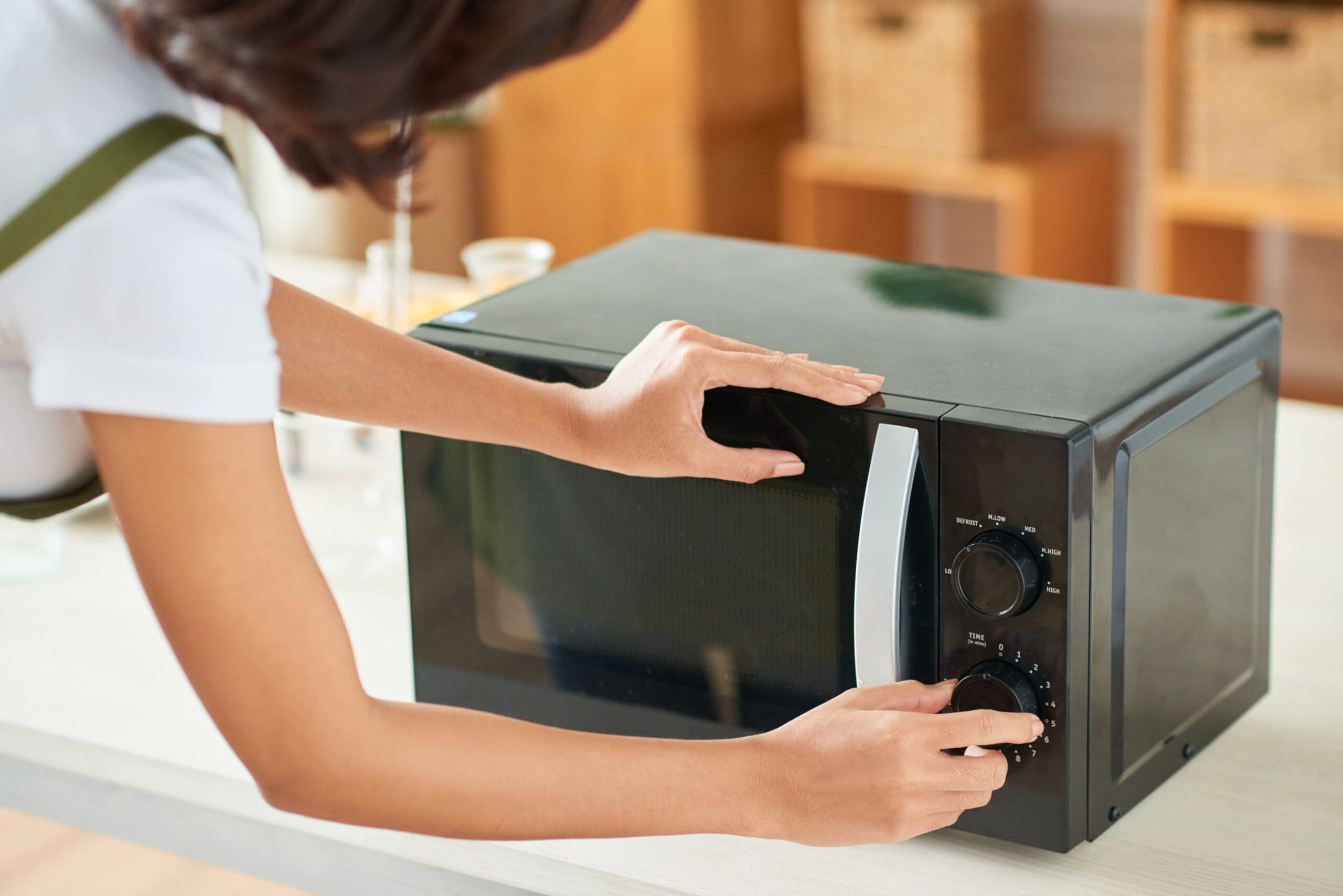 Woman in office kitchen using the microwave to make her lunch