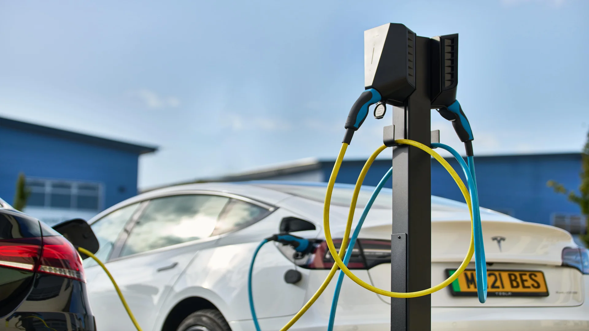 Two electric vehicles plugged into an electrical charge point